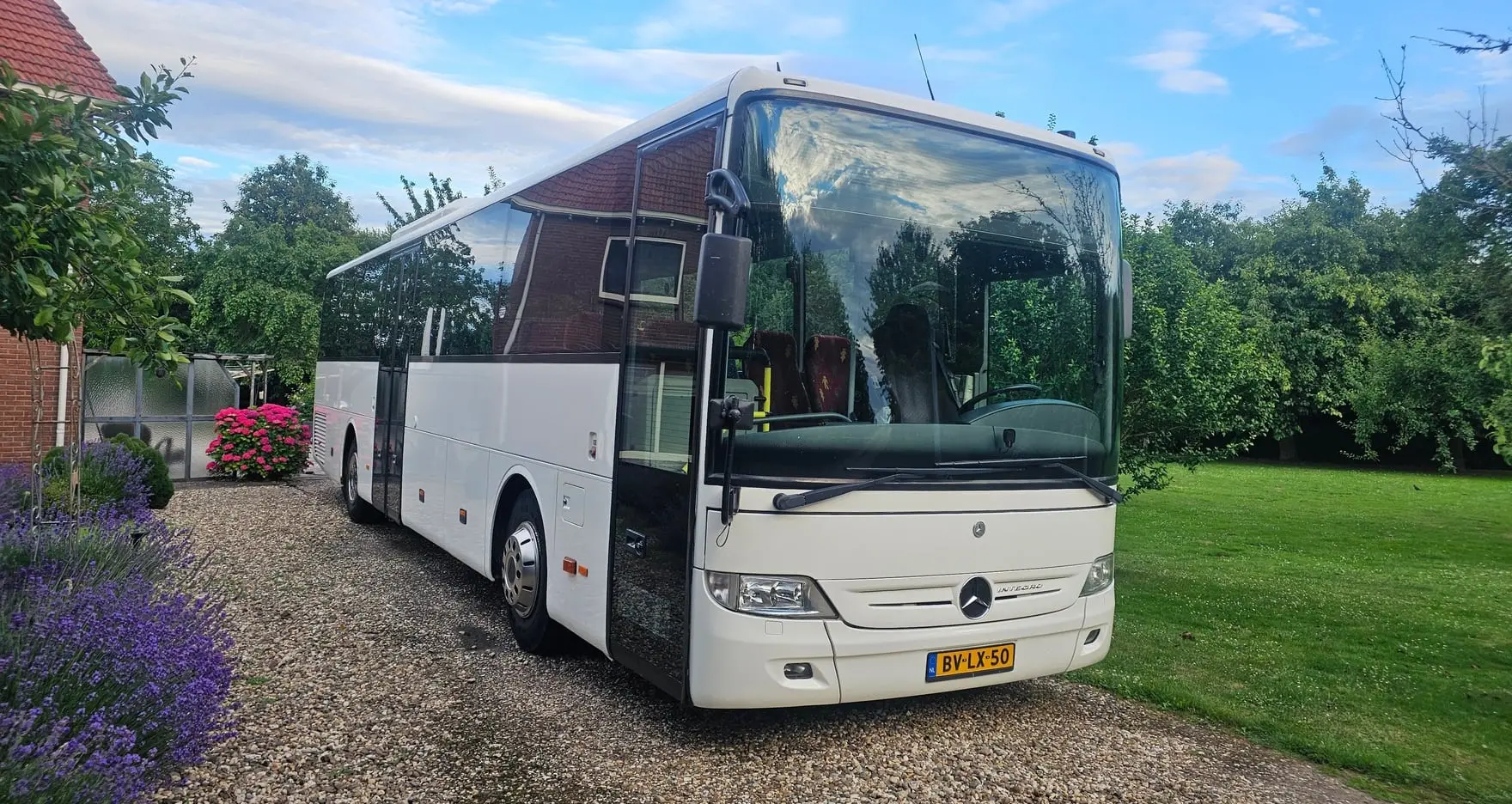 Bus van RT Reizen driekwart van voren op de oprit, kenteken BV-LX-50.