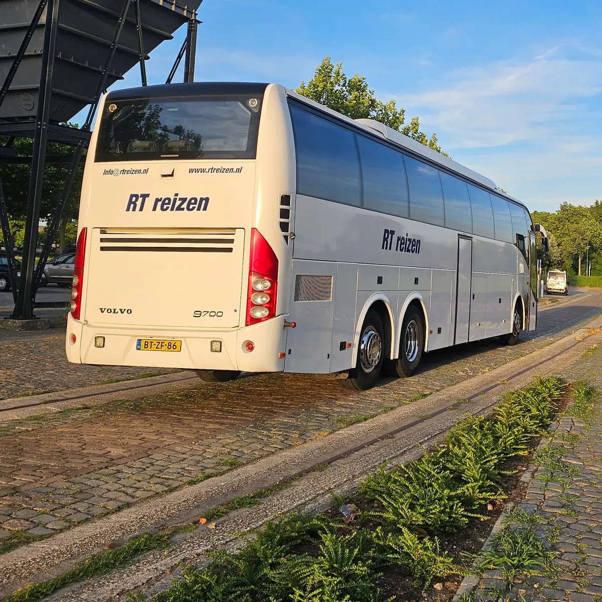 Achterkant van de touringcar van RT Reizen op de kade in Doesburg, met de naam op de bus.