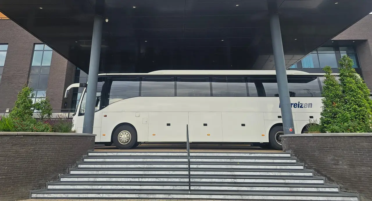 Touringcar van RT Reizen voor de ingang van Van der Valk Duiven, klaar om een groep op te halen.