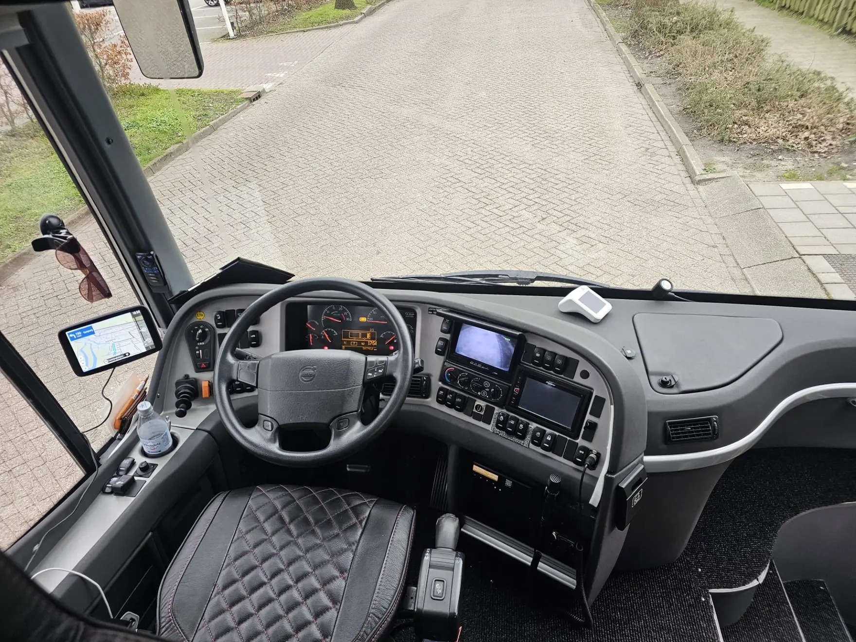 De chauffeursplaats van de touringcar, met stuur, dashboard en uitzicht door de voorruit.