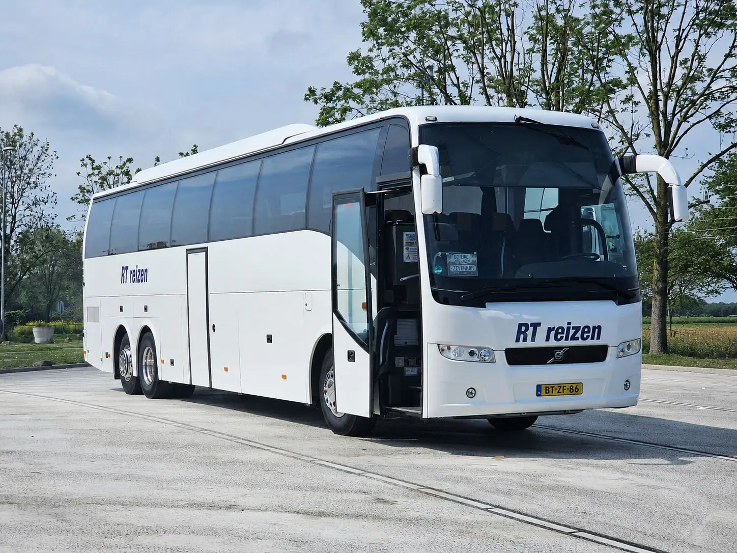Touringcar van RT Reizen met open deur, klaar om een groep te laten instappen.