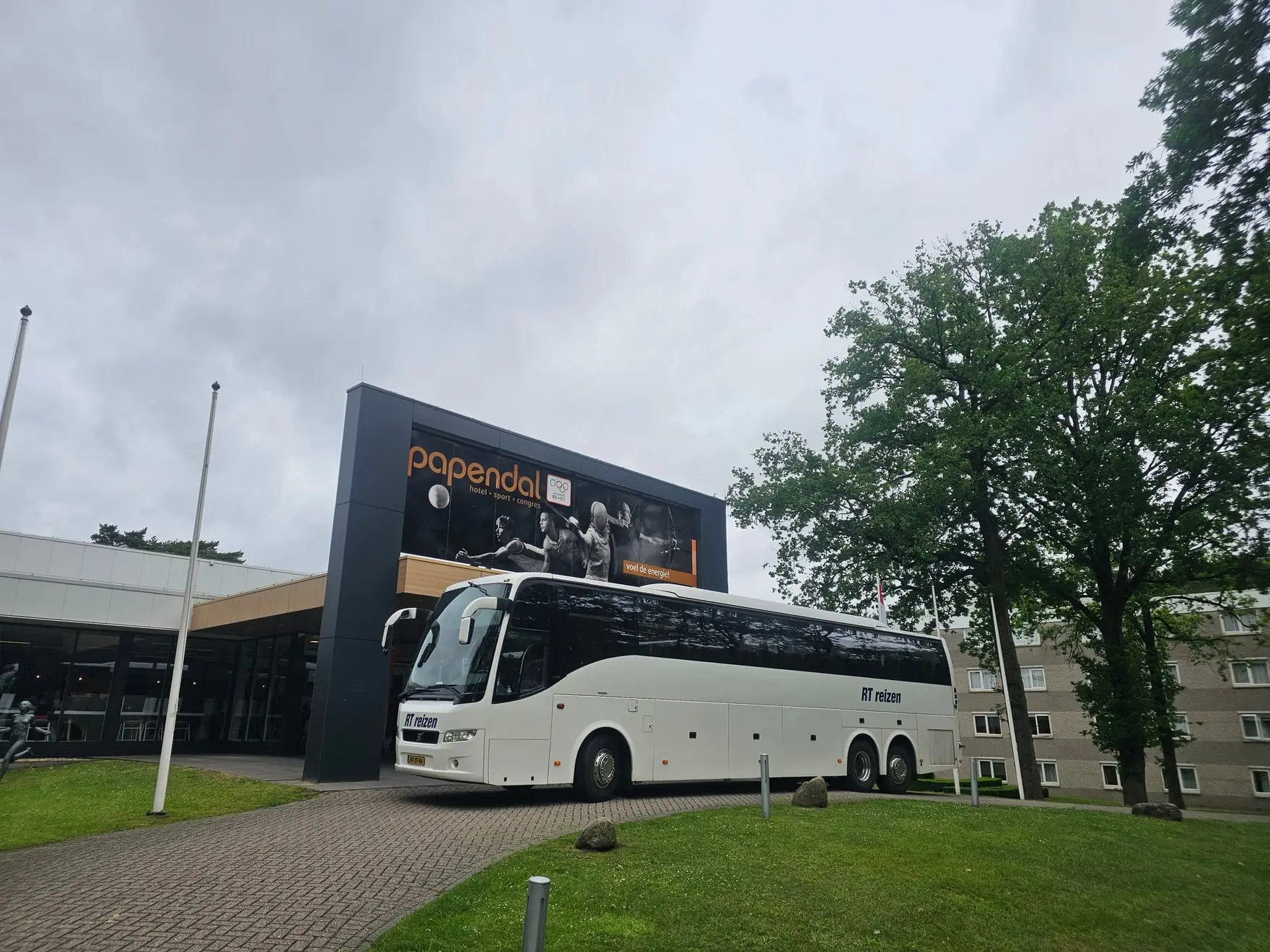 Touringcar van RT Reizen voor de ingang van sportcentrum Papendal.
