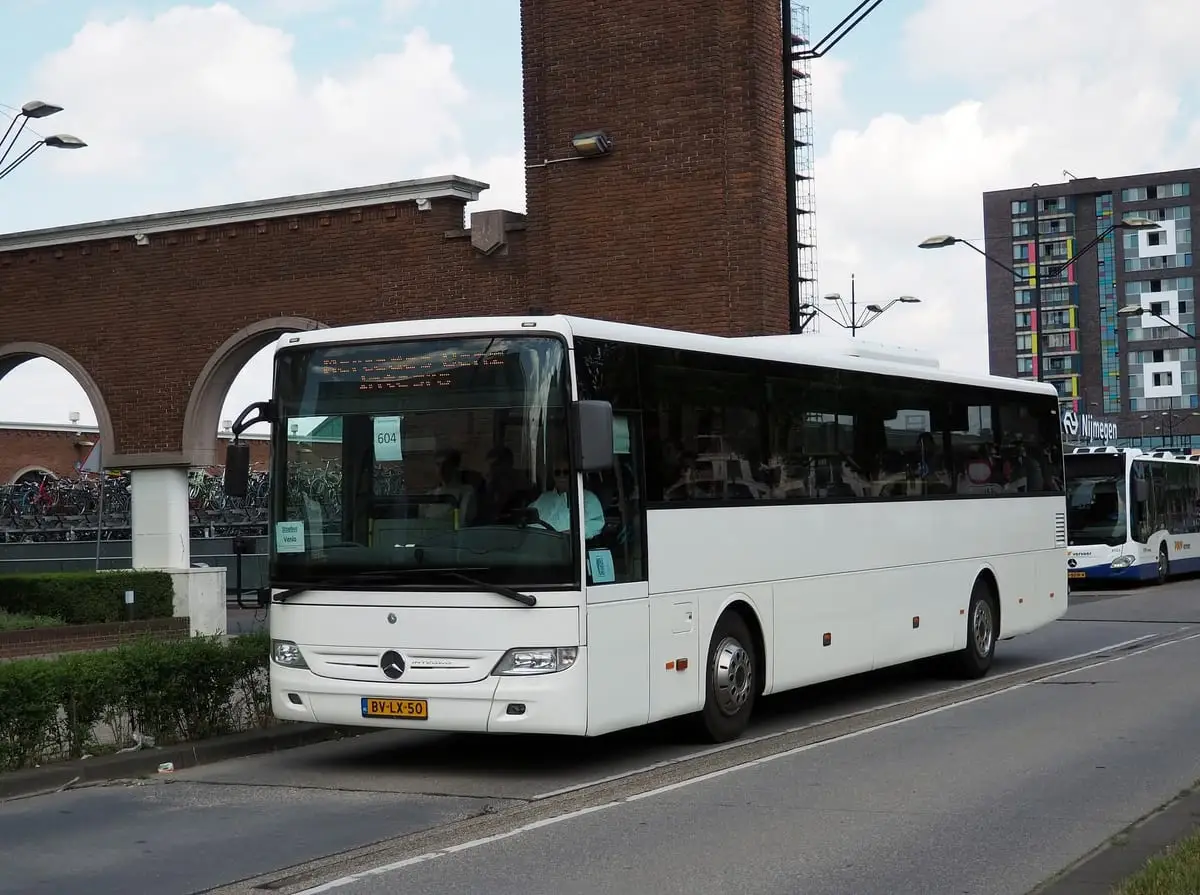 De bus van RT Reizen bij een station, klaar om een groep op te halen.